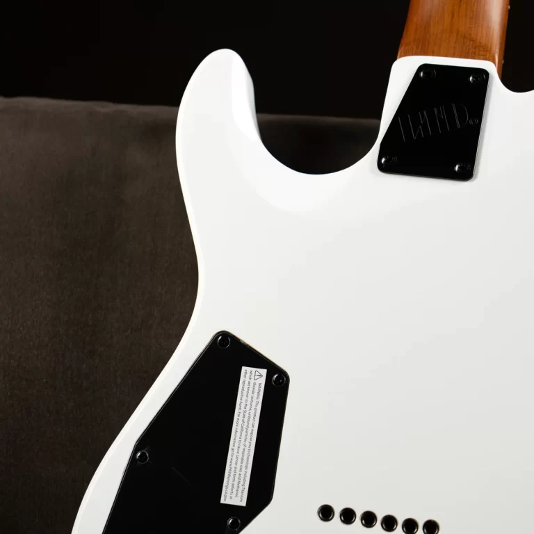 Rear view of a white electric guitar showing black plate covers and a wooden neck on a dark surface. ขายราคาพิเศษ