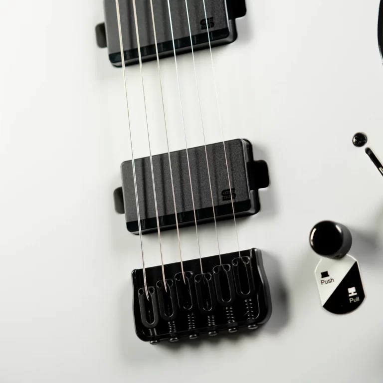 Close-up of an electric guitar body showing two black humbucker pickups, strings, and the bridge anchored to a white surface. ขายราคาพิเศษ