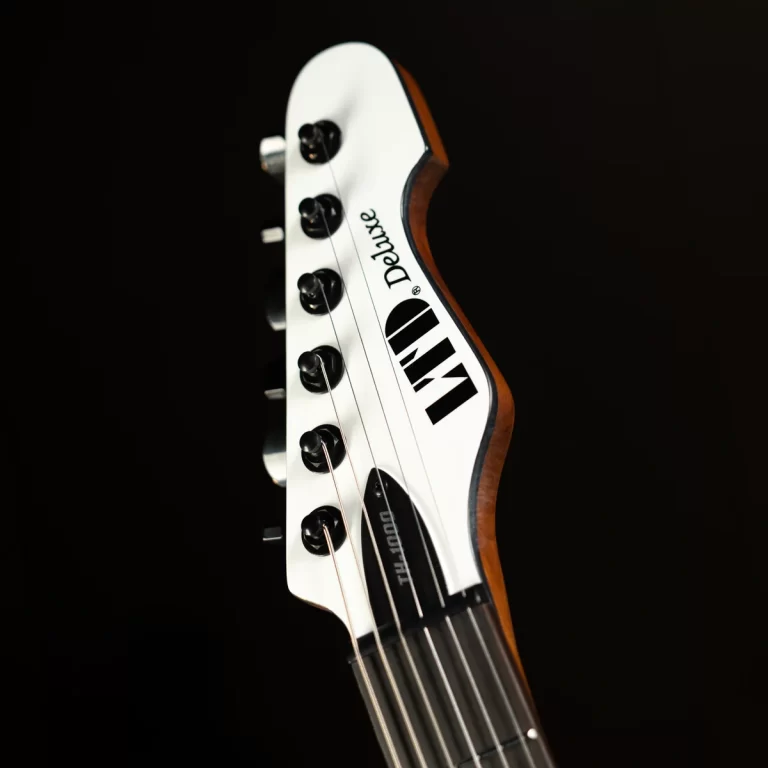 Close-up of a white guitar headstock with six tuning pegs and strings against a dark background. ขายราคาพิเศษ