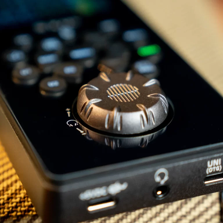 Close-up of a metallic rotary knob on a black control panel, with a textured edge and reflection in the surface. ขายราคาพิเศษ