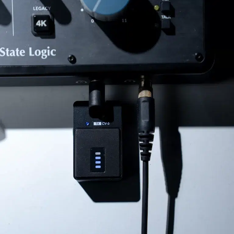 Close-up of a black audio rack panel labeled 'State Logic' with two cables connected to a small transmitter module marked TX-CV-3 and blue LED indicators visible. ขายราคาพิเศษ