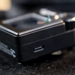Close-up of a black electronic device showing a USB-C port on the side, with blurred cables in the background. ขายราคาพิเศษ