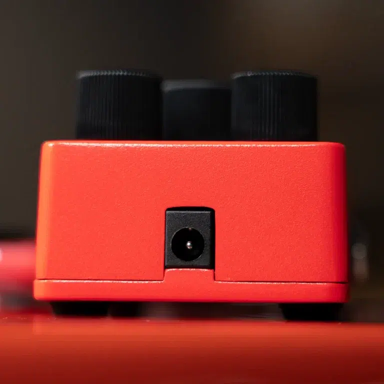 Red guitar effects pedal front view with two black knobs on top and a centered input jack on the front face. ขายราคาพิเศษ