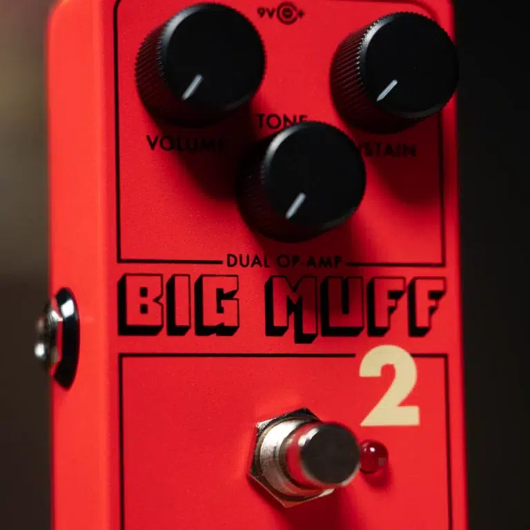 Close-up of a red Big Muff guitar pedal with three black knobs labeled Volume, Tone, Sustain and a pedal switch with a small LED eyelet nearby, 'Big Muff' in bold letters. ขายราคาพิเศษ