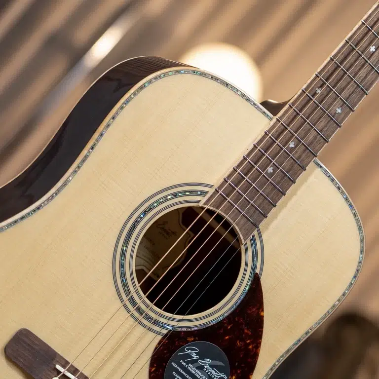 Close-up of an acoustic guitar body and neck, showcasing the light wood top, rosette, and six strings. ขายราคาพิเศษ