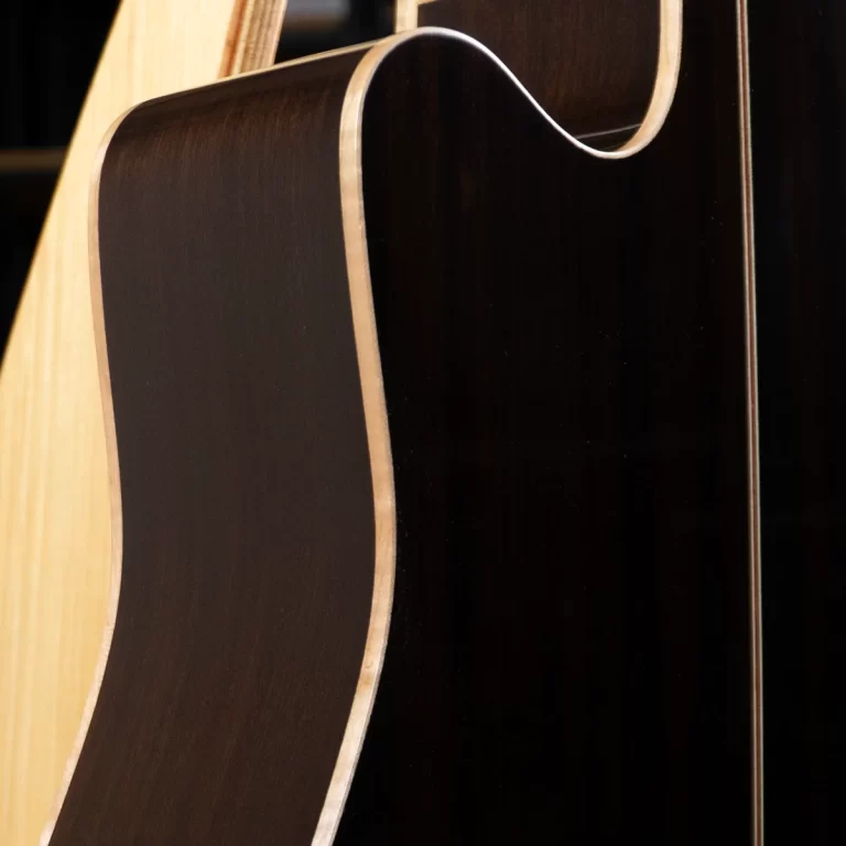Close-up of an acoustic guitar body showing the dark back and light side wood with a tan binding edge ขายราคาพิเศษ