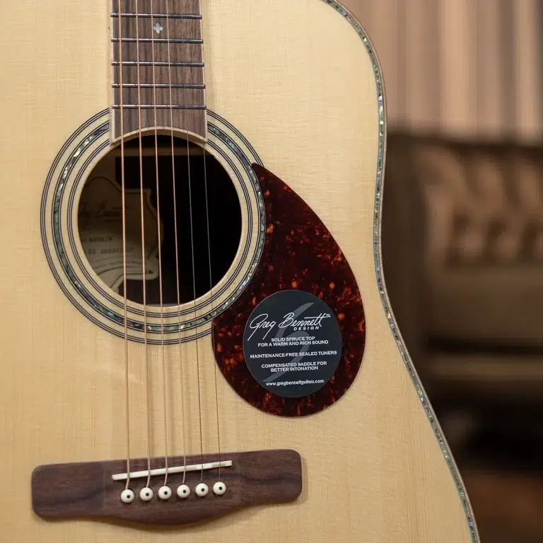 Close-up of an acoustic guitar body with soundhole, strings, and a tortoiseshell pickguard showing a circular label. ขายราคาพิเศษ