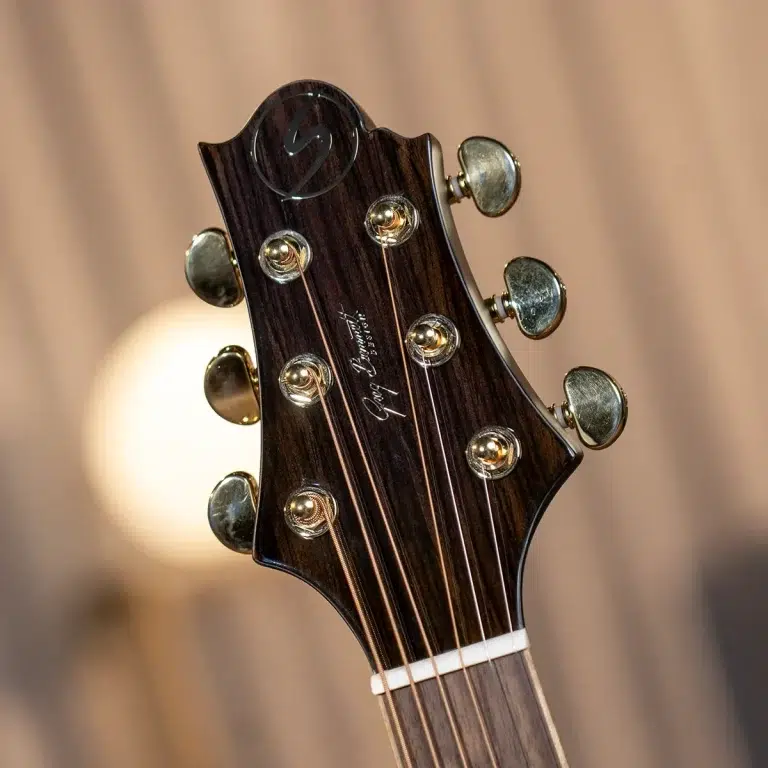 Close-up of a dark wooden guitar headstock with six tuning pegs and strings. ขายราคาพิเศษ