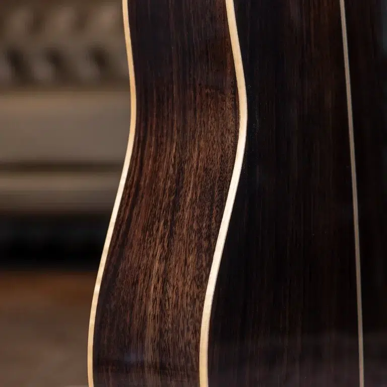 Close-up of a dark wood guitar body with cream-colored binding along the edge. ขายราคาพิเศษ