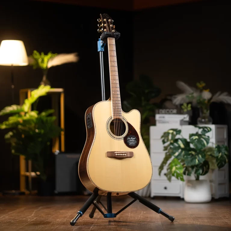 Acoustic guitar on a stand in a cozy studio setting with warm lighting and green plants in the background. ขายราคาพิเศษ