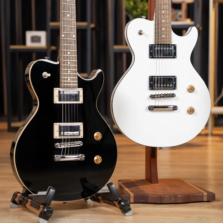 Two electric guitars, black and white, on stands in a guitar shop with a wooden floor and shelving in the background. ขายราคาพิเศษ