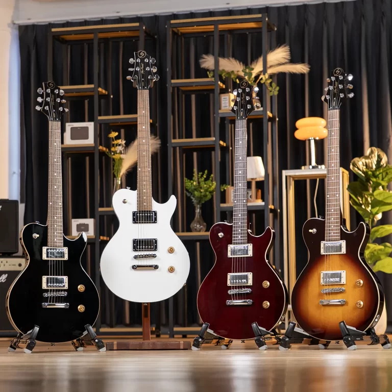 Four electric guitars on stands in a showroom with a white center guitar and sunburst models nearby. ขายราคาพิเศษ