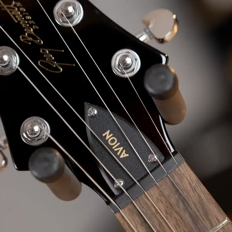 Close-up of a black guitar headstock with six strings, tuning pegs, and a gold Gibson logo partially visible. ขายราคาพิเศษ