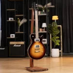 Sunburst electric guitar on a wooden stand in a showroom with amplifiers in the background. ขายราคาพิเศษ