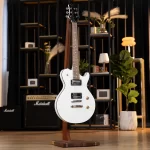 White electric guitar on a wooden stand in a music store, with Marshall amplifiers and shelves in the background. ขายราคาพิเศษ