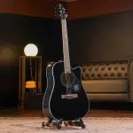 Black acoustic guitar on a stand in a dim, cozy room with a round lamp and tufted sofa in the background.”](https://) ขายราคาพิเศษ
