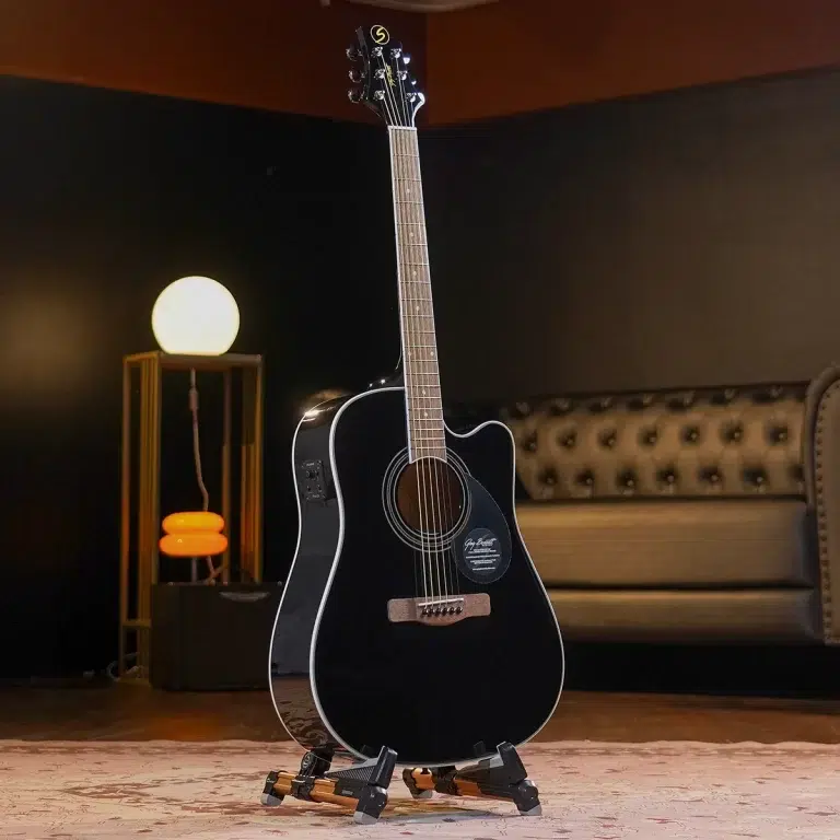 Black acoustic guitar on a stand in a dim, cozy room with a round lamp and tufted sofa in the background.”](https://) ขายราคาพิเศษ