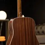 Close-up of the back and neck of a brown polished acoustic guitar with white binding. ขายราคาพิเศษ