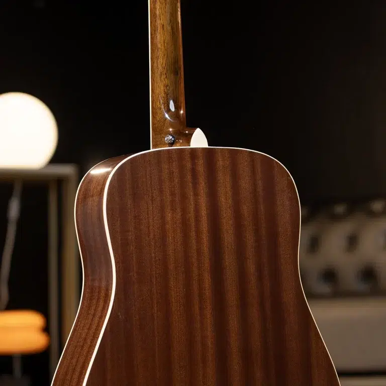 Close-up of the back and neck of a brown polished acoustic guitar with white binding. ขายราคาพิเศษ