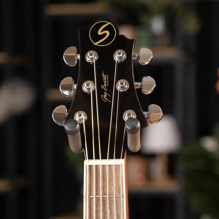 Close-up of a black guitar headstock with six chrome tuners and the gold 'Greg Bennett Design' logo on a dark finish. ขายราคาพิเศษ