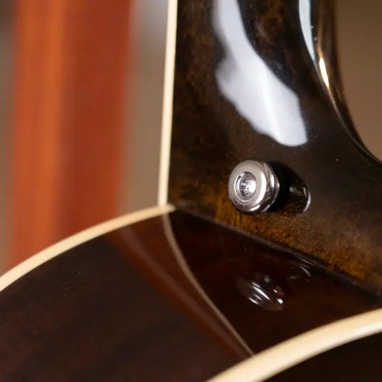 Close-up of a glossy dark guitar body showing a chrome strap button near the edge. ขายราคาพิเศษ