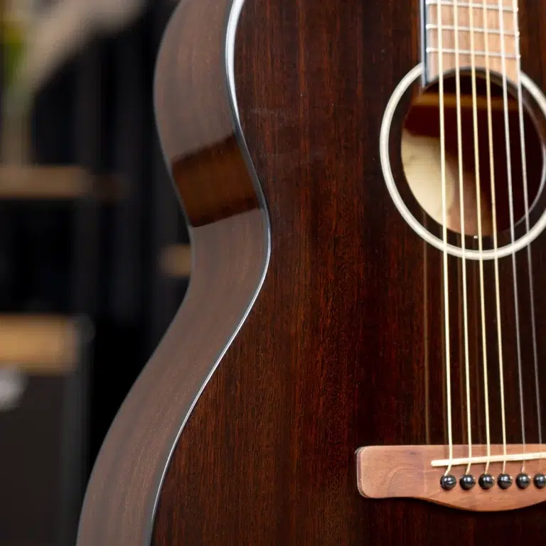 Close-up of a dark wood acoustic guitar showing the body, strings, and soundhole edge. ขายราคาพิเศษ