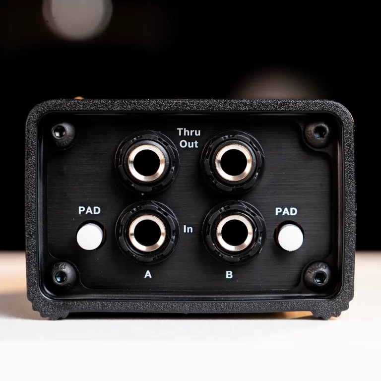 Front panel of a small black audio device showing four circular 1/4-inch jacks labeled A, B, Thru, and Out, with two white PAD buttons on either side. ขายราคาพิเศษ