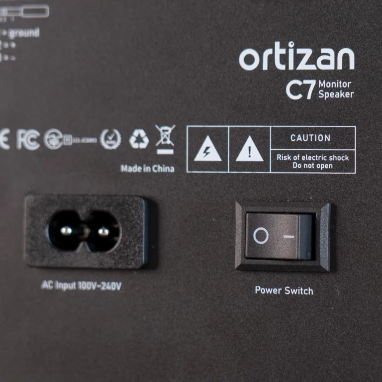 Rear panel of Ortizan C7 monitor speaker with power switch and AC input socket, plus caution icons. ขายราคาพิเศษ