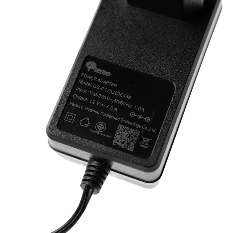 Close-up of a black power adapter plugged in, showing the label with model and input/output specs (e.g., 100-240V, output 12V). ขายราคาพิเศษ