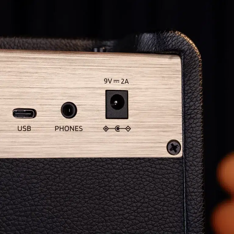 Back panel showing USB port, headphone jack labeled PHONES, and 9V 2A power input on a brushed metal surface with black textured casing. ขายราคาพิเศษ
