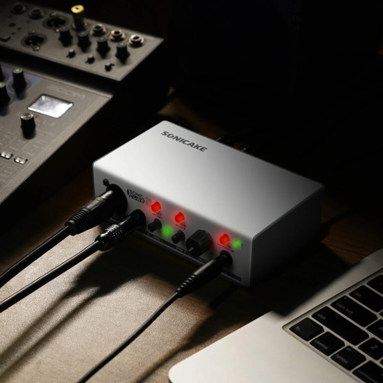 Audio interface with multiple input cables connected and LED indicators on, sitting beside a laptop on a desk. ขายราคาพิเศษ