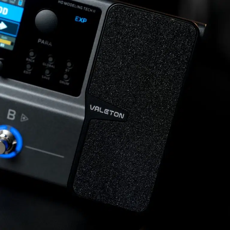 Close-up of a textured black Valeton guitar effects pedal with the brand name visible beside other control knobs and panels. ขายราคาพิเศษ