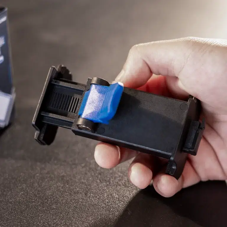 Hand holding a black printer toner cartridge with blue protective tape on the end, ready for replacement ขายราคาพิเศษ