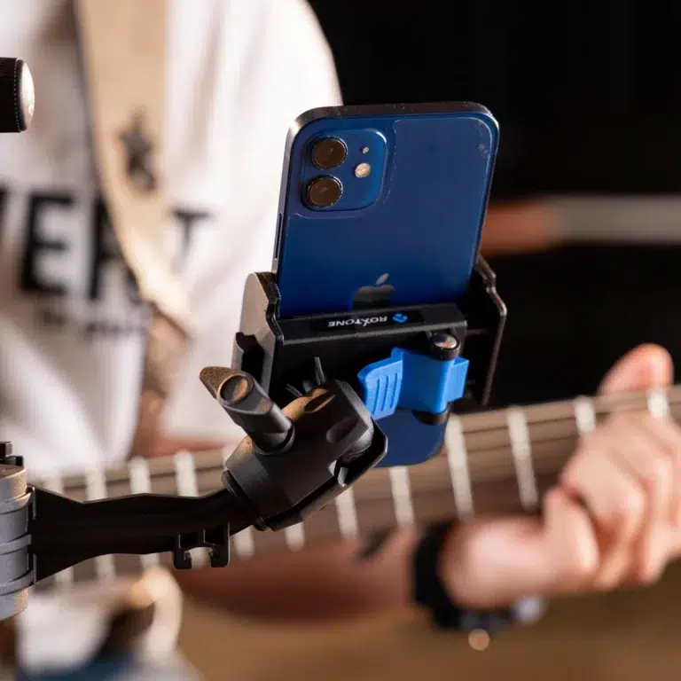 Blue iPhone mounted in a robotic gripper above a guitar neck, camera lenses in focus. ขายราคาพิเศษ