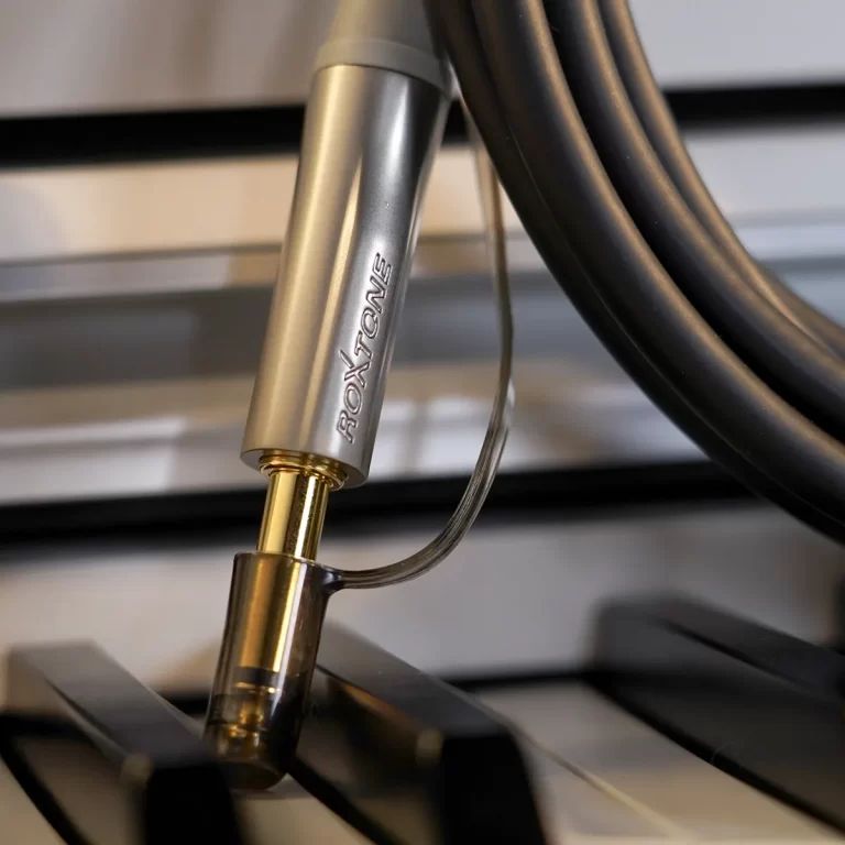 Close-up of a RoxTone metal probe with a cable, resting on a piano keyboard key (sensor/measurement setup). ขายราคาพิเศษ