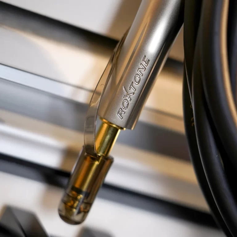 Close-up of a silver connector with a gold tip attached to a black cable, showing engraved lettering on the metal. ขายราคาพิเศษ