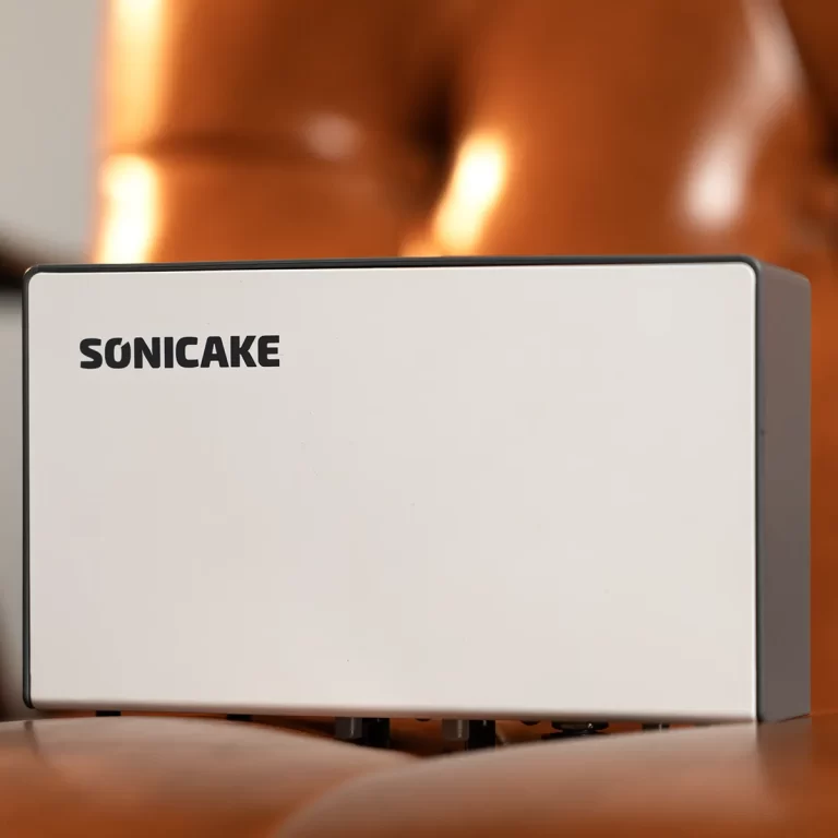White rectangular electronic device with the brand name SONICAKE on the front, sitting on a wooden surface against a warm, blurred background. ขายราคาพิเศษ