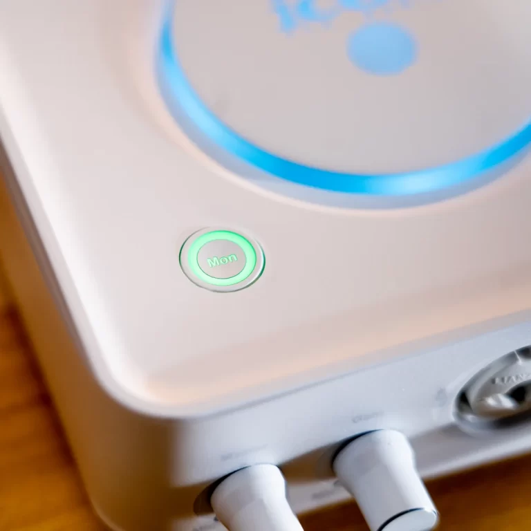 Close-up of a circular green-lit button labeled 'Mon' on a white appliance. ขายราคาพิเศษ