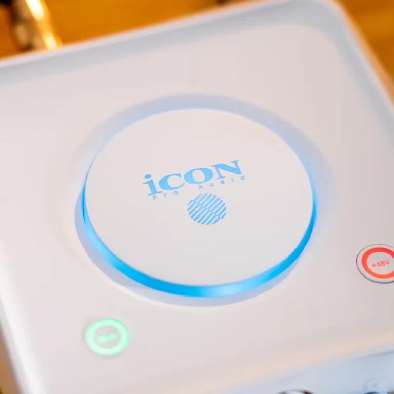 Close-up of a white Icon Pro Audio device with a glowing blue ring around a circular control and brand logo. ขายราคาพิเศษ