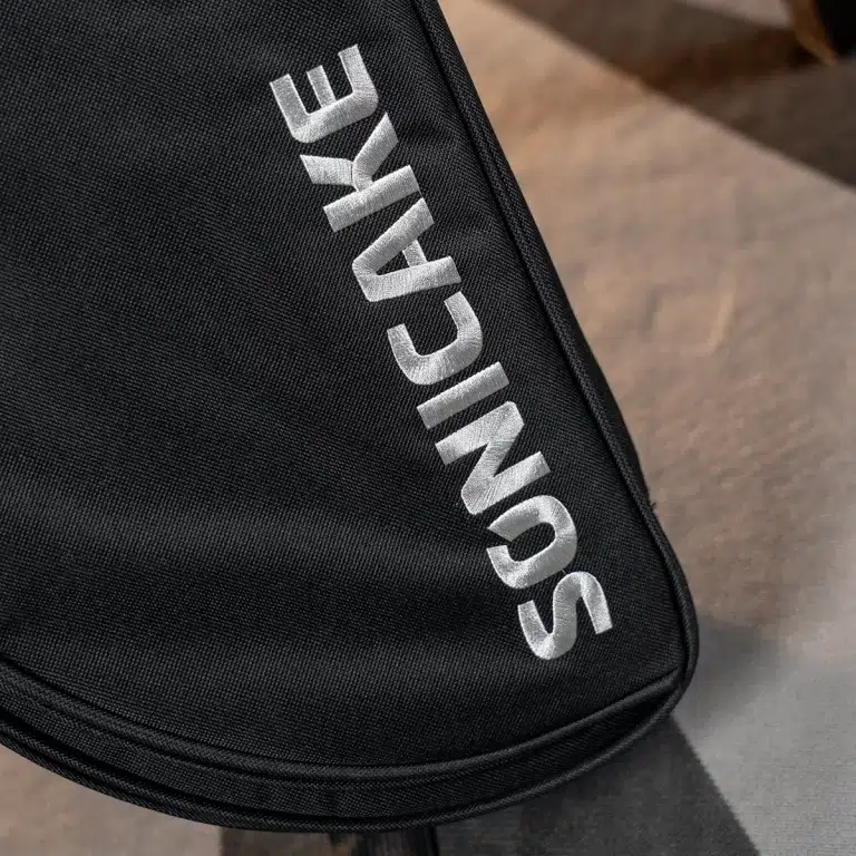 Close-up of a black fabric bag with bold silver embroidered vertical text along the edge. ขายราคาพิเศษ