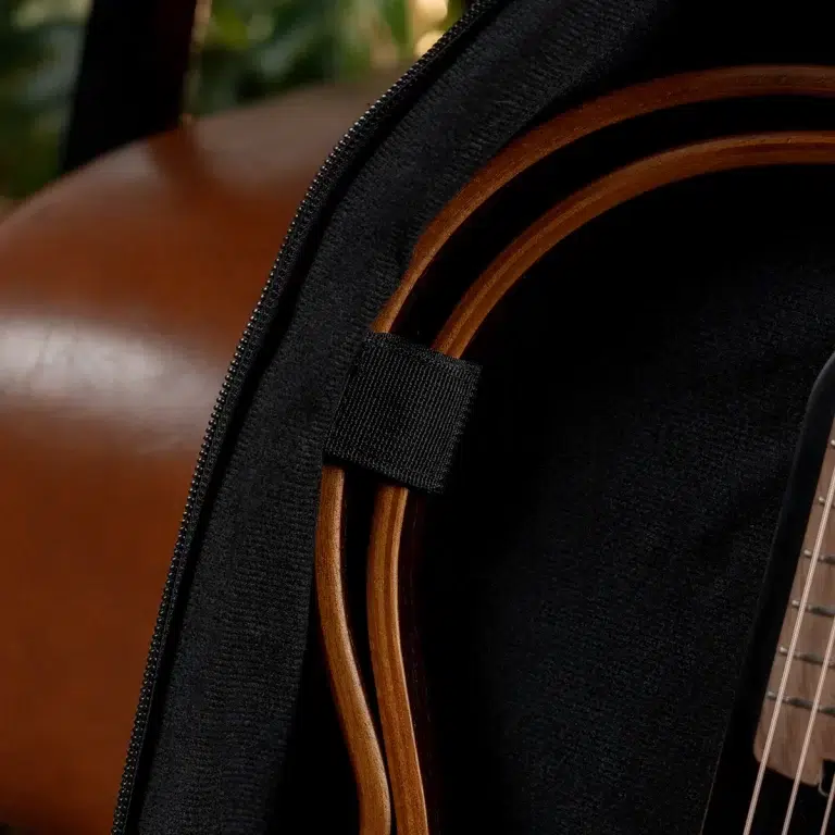 Close-up of an acoustic guitar tucked inside a black padded case with a zipper visible at the edge. ขายราคาพิเศษ