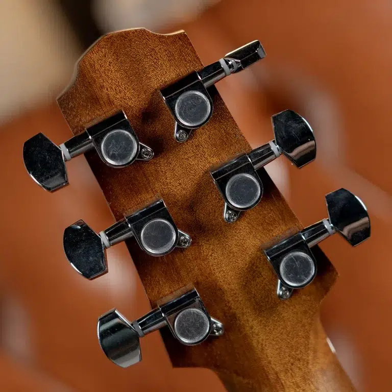 Close-up of a guitar headstock with chrome tuning pegs on a brown wooden neck. ขายราคาพิเศษ