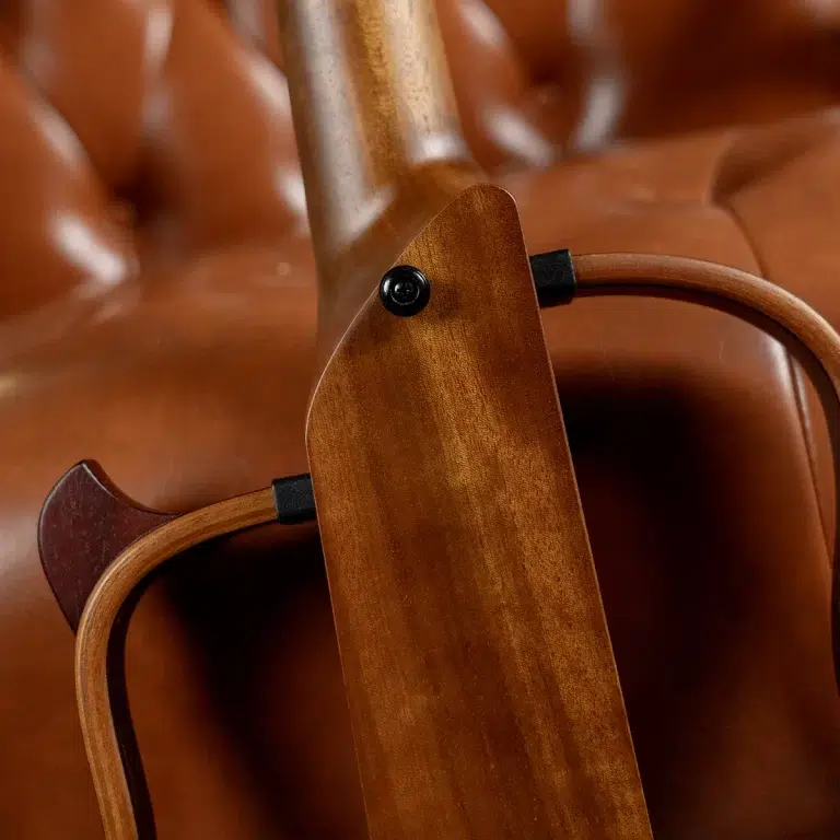 Close-up of a wooden chair frame showing a black screw and curved armrest. ขายราคาพิเศษ