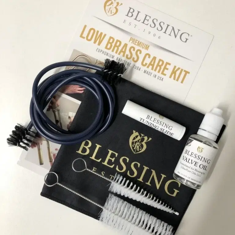 Blessing low brass care kit laid out on a black cloth: cleaning brushes, flexible tubing, valve oil bottle, and cloth pouch with Blessing branding. ขายราคาพิเศษ