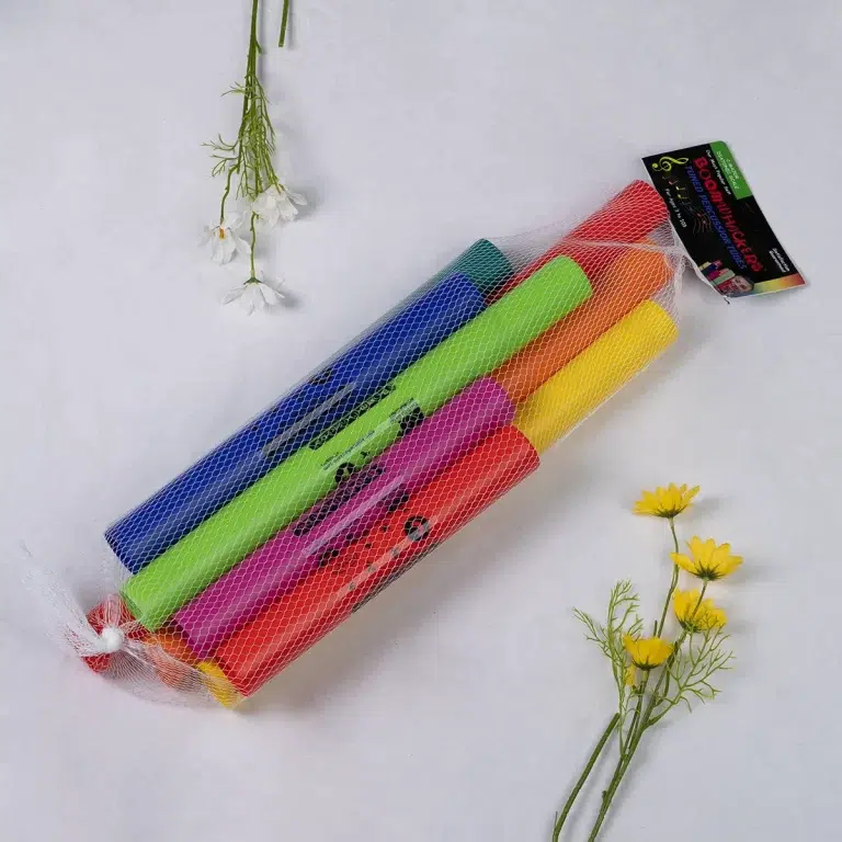 Bundle of neon-colored chalk sticks in a white mesh bag diagonally placed on a light background, with small white flowers nearby. ขายราคาพิเศษ