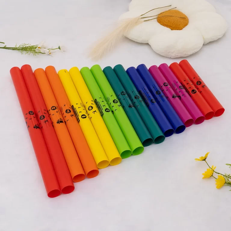 Row of rainbow-colored markers arranged in a diagonal line on a light surface, with a white flower plush and small flowers in the background. ขายราคาพิเศษ