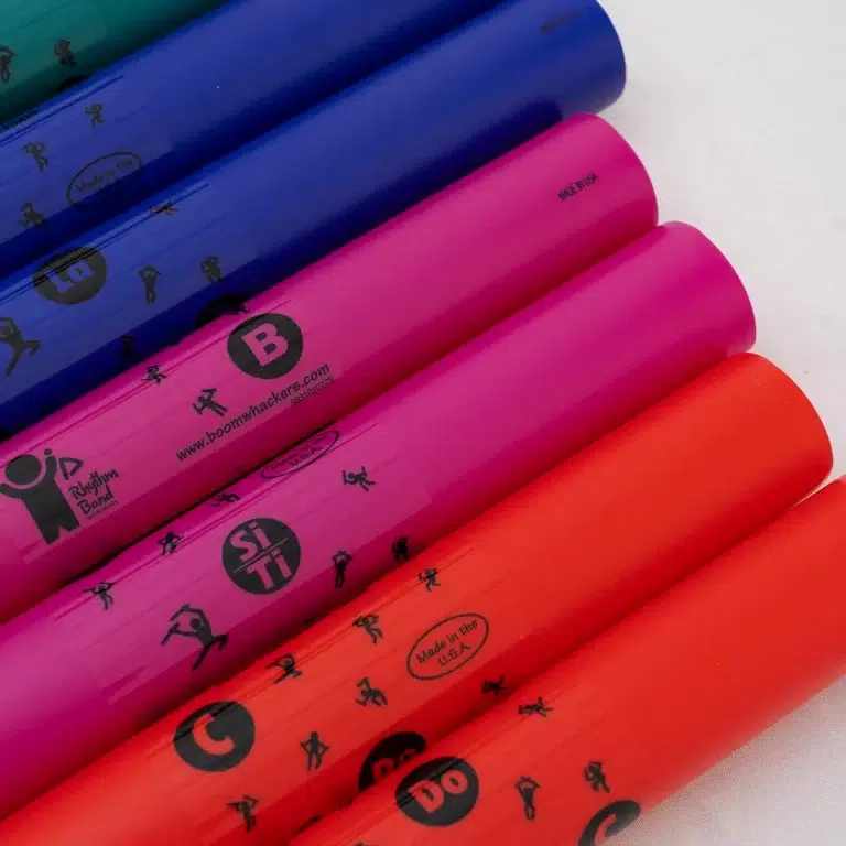 Row of colorful Boomwhacker tubes in blue, purple, pink, and red laid diagonally on a white surface. ขายราคาพิเศษ