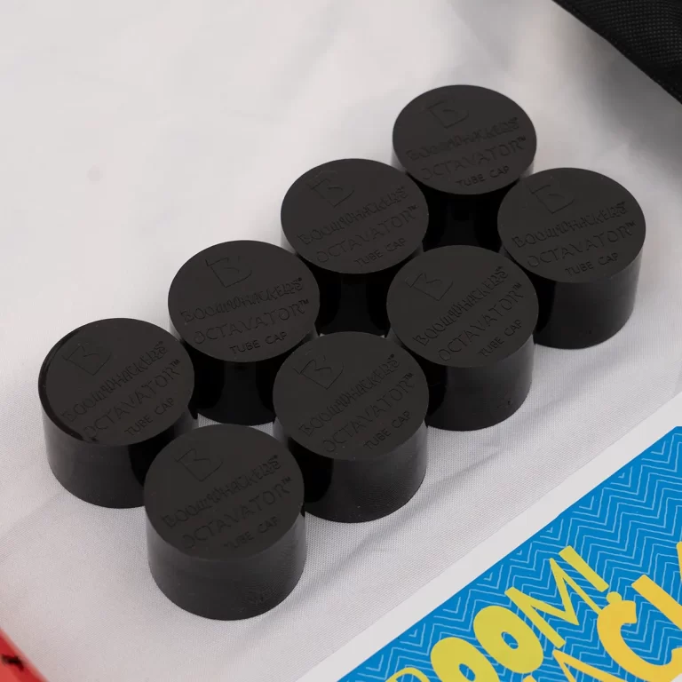 Cluster of black plastic tube caps labeled 'Boomwhackers Octavator Tube Cap' arranged on a white surface. ขายราคาพิเศษ