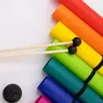 Rainbow row of rolled foam mats diagonally with two wooden drumsticks crossing them. ขายราคาพิเศษ
