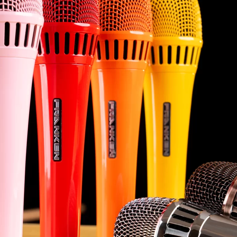 Row of colorful handheld microphones in pink, red, orange, and yellow against a dark background ขายราคาพิเศษ